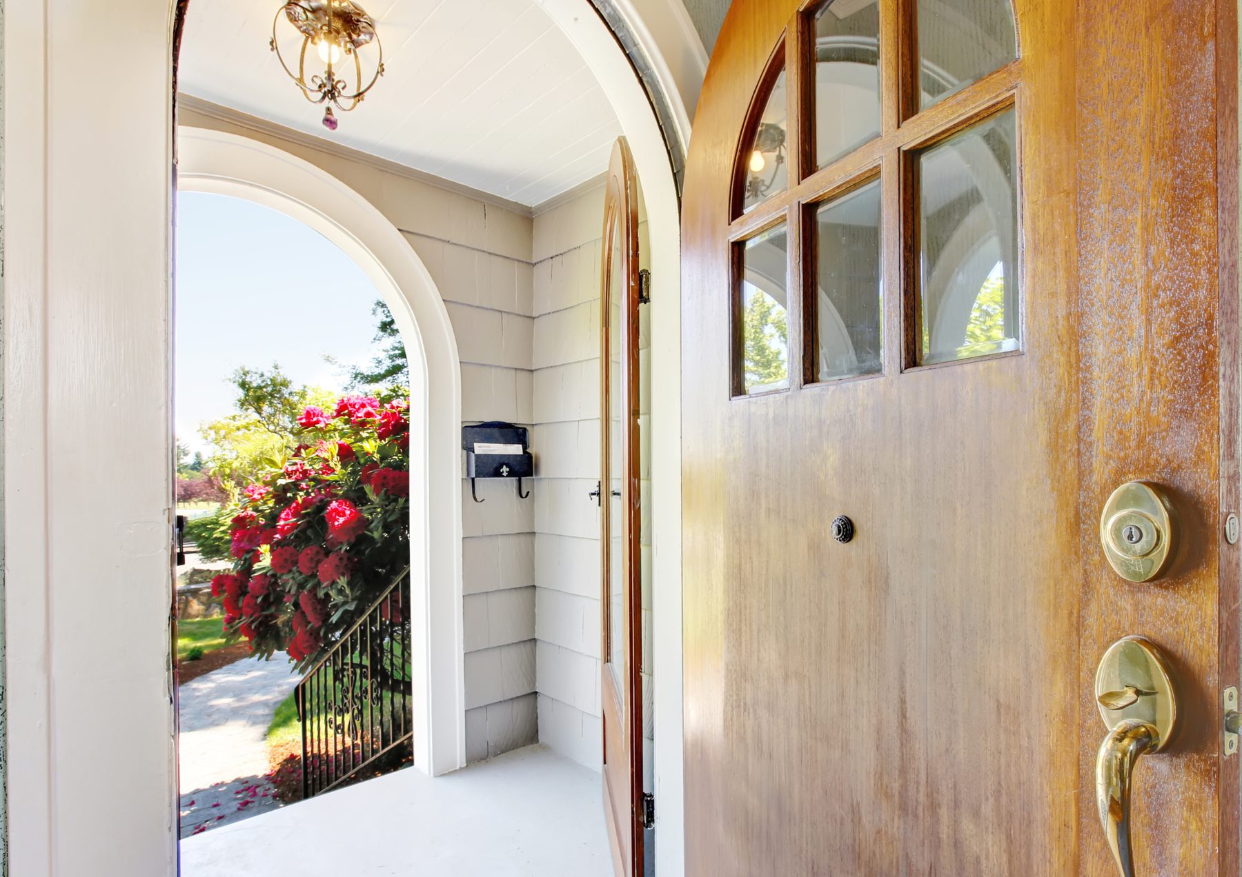 An arched front door open onto a sunlit garden